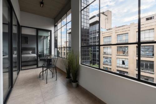 a room with windows and a bed and a table at Zielo Rentals Palma ,Private balcony, Rooftop Walk to Zocalo in Mexico City