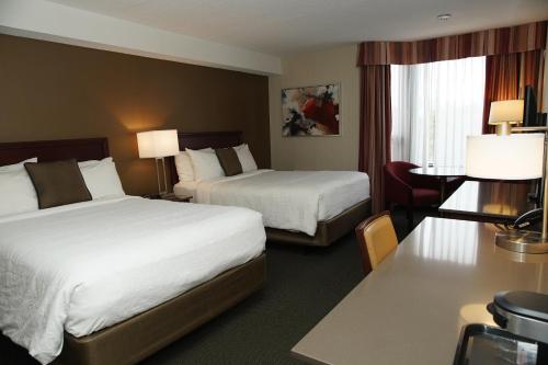 a hotel room with two beds and a desk at Hôtel WelcomInns in Boucherville