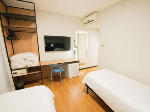 a room with two beds and a desk with a television at ibis Curitiba Shopping in Curitiba