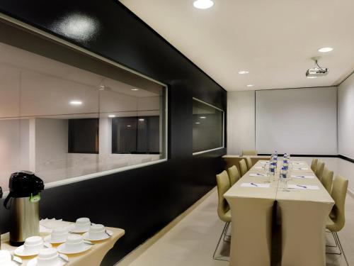 a conference room with a table and chairs and a screen at ibis Curitiba Shopping in Curitiba