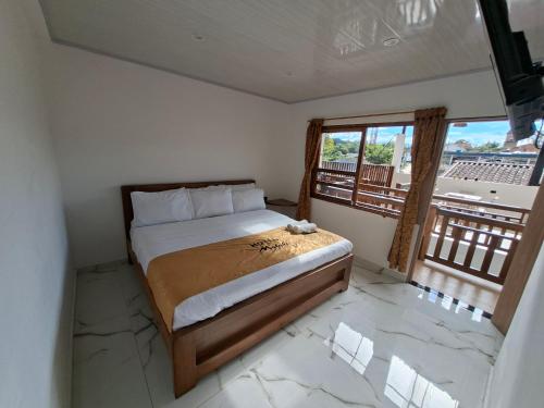 a bedroom with a bed with a view of a balcony at Hotel Malaki in San Agustín
