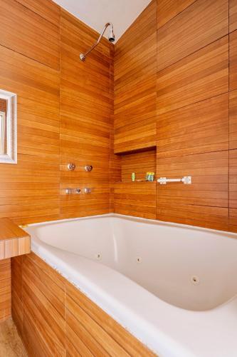 a large white bath tub in a bathroom with wooden walls at Loft lujo estilo y diseño, alberca, Cuernavaca somos los únicos en ofrecerte 2 jacuzzis tipo Spa con agua caliente y sistema de hidromasaje, alberca con calefacción ecológica, amplia cama de alberca, 3 pantallas, terraza privada con asador de carbon, WiFi in Cuernavaca