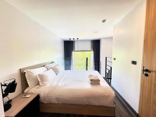 a bedroom with a large bed with white sheets at Utopia Loft Condo Naiharn Beach in Nai Harn Beach
