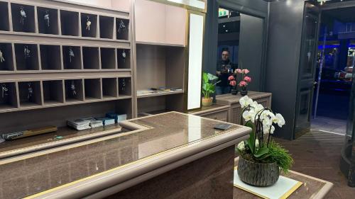 a woman standing in a dressing room with a vase of flowers at Hotel Deutsches Theater Landwehrstraße in Munich