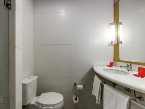 a white bathroom with a toilet and a sink at ibis Jaboticabal in Jaboticabal