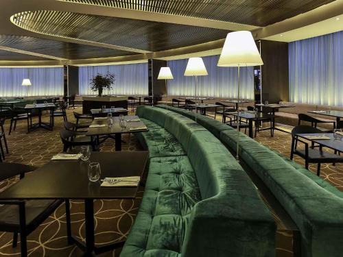 a restaurant with a long green couch in the middle at Novotel Sydney West HQ in Rooty Hill