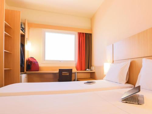 a hotel room with a bed and a window at ibis Montes Claros Shopping in Montes Claros
