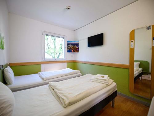 a room with two beds and a mirror at Ibis budget Koeln Messe in Cologne