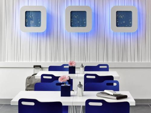 a dining room with blue chairs and a table with flowers at Ibis budget Koeln Messe in Cologne