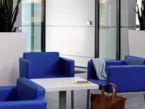 a group of blue chairs and a table in a room at Ibis budget Koeln Messe in Cologne