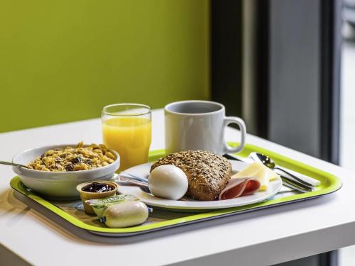 a breakfast tray with eggs and a cup of orange juice at Ibis budget Koeln Messe in Cologne