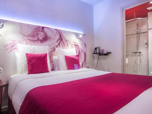 a bedroom with a large bed with pink and white pillows at Mercure Paris Bastille Marais in Paris