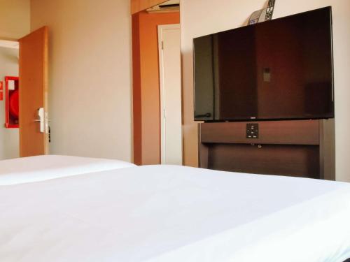 a hotel room with a bed and a flat screen tv at ibis Santiago Providencia in Santiago