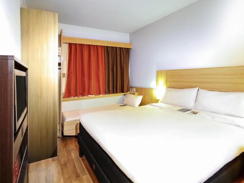 a hotel room with a large bed and a television at ibis Santiago Providencia in Santiago