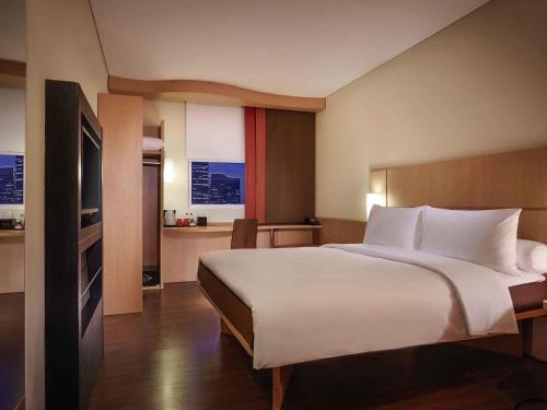 a hotel room with a large bed and a television at Ibis Surabaya City Center in Surabaya