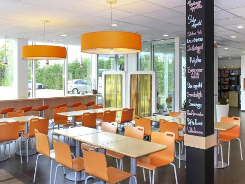 a dining room with tables and chairs and windows at ibis budget Antwerpen Port in Antwerp