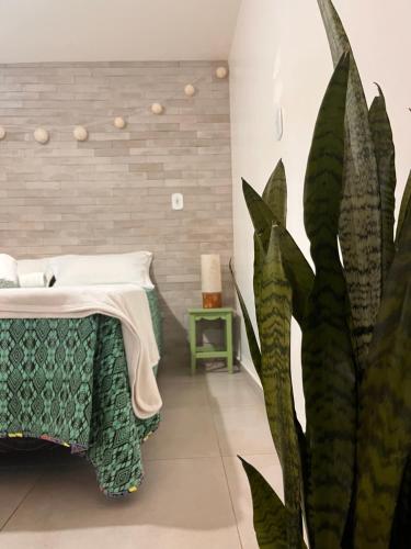 une chambre avec un lit et une plante dans l'établissement Casa Bom Viver, à Arraial do Cabo