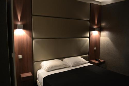 a bedroom with a bed with a black headboard and two lights at Hotel Schtak in Cannes