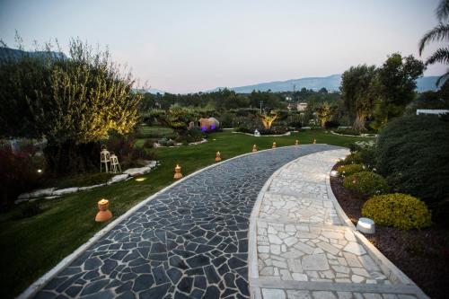 a cobblestone walkway in a garden with trees at Villa Caribe Resort & Spa in Spigno Saturnia