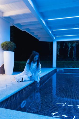 a woman sitting on the edge of a swimming pool at Villa Caribe Resort & Spa in Spigno Saturnia