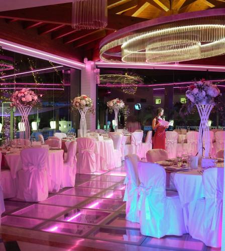 a banquet hall with white tables and chairs and a woman at Villa Caribe Resort & Spa in Spigno Saturnia