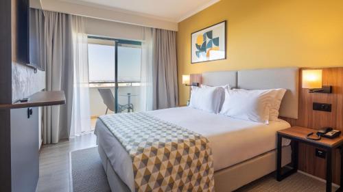 a hotel room with a large bed and a window at Holiday Inn Algarve Albufeira by IHG in Albufeira