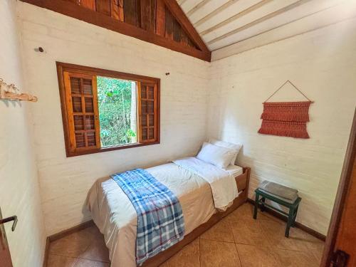 a small bedroom with a bed and a window at Cabana Arara - Terroir Mantiqueira in Paiol Grande