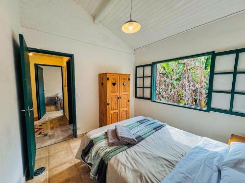 a bedroom with a bed and a large window at Cabana Catuaí - com piscina privativa in Paiol Grande