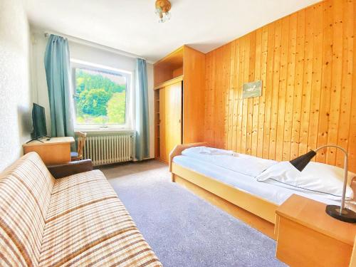 a bedroom with a bed and a couch and a window at Zum Goldenen Löwen in Oberzent