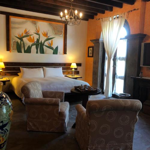 a hotel room with a bed and two chairs at Posada de las Flores Loreto in Loreto