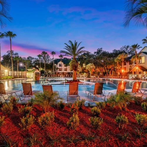 a resort pool with chairs and palm trees at night at Pool Gym & Extended Stays Budget Frienly in Tampa