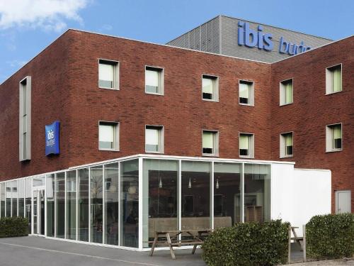 a large red brick building with auss building at ibis Budget Brussels South Ruisbroek in Ruisbroek