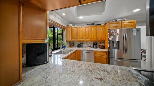 a kitchen with wooden cabinets and a stainless steel refrigerator at Luxury Queen Room, Walk to UM, Free Car Service! in Miami