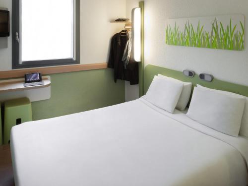 a large white bed in a room with a window at ibis Budget Brussels South Ruisbroek in Ruisbroek