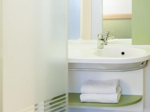 a bathroom with a sink and a mirror and towels at ibis Budget Brussels South Ruisbroek in Ruisbroek