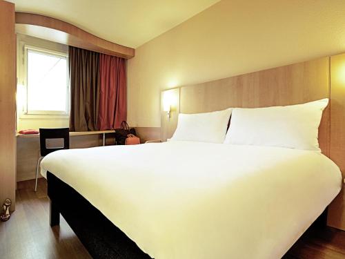 a large white bed in a hotel room at ibis Delémont in Delémont