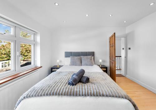 a bedroom with a large bed and two windows at The Aviator Heathrow in Harmondsworth