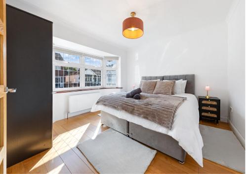 a bedroom with a large bed and two windows at The Aviator Heathrow in Harmondsworth