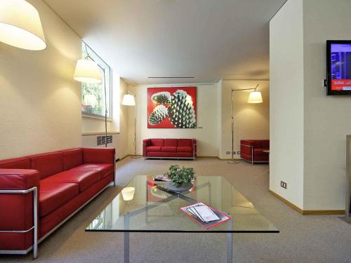 a living room with a red couch and a glass table at Hotel Mercure Milano Solari in Milan