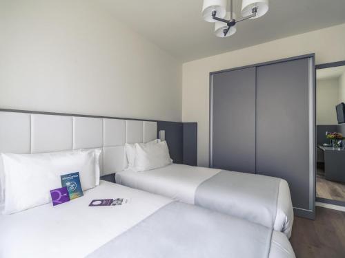 two beds in a hotel room with white sheets at Hotel Mercure Milano Solari in Milan