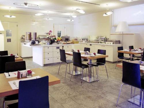 a room with tables and chairs and a kitchen at Hotel Mercure Milano Solari in Milan