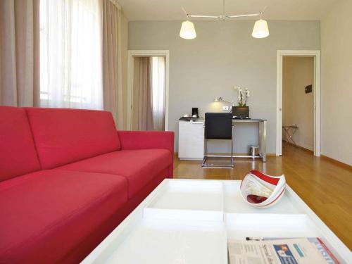 a living room with a red couch and a table at Hotel Mercure Milano Solari in Milan