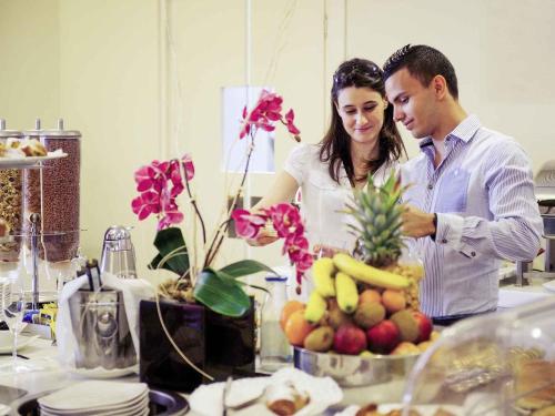 a man and woman standing in a kitchen preparing food at Hotel Mercure Milano Solari in Milan