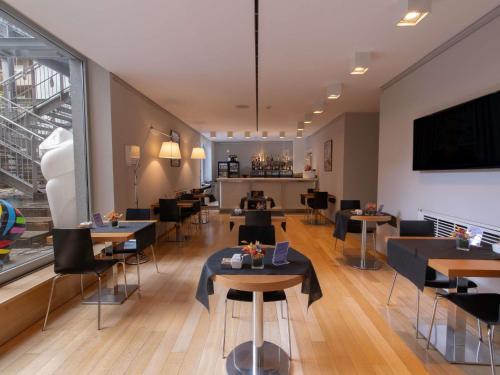 a restaurant with tables and chairs and a large window at Hotel Mercure Milano Solari in Milan
