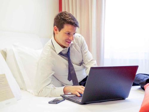 a man in a suit and tie using a laptop computer at Hotel Mercure Milano Solari in Milan