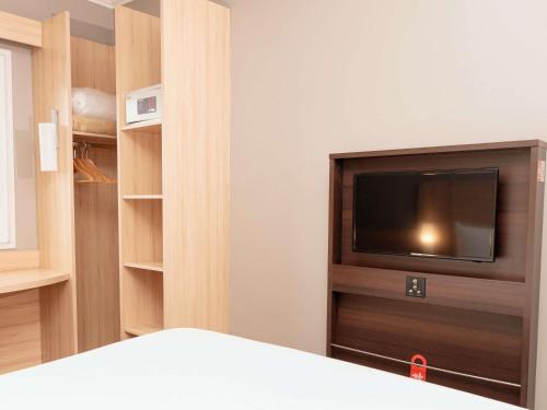 a bedroom with a bed and a tv and shelves at ibis Santiago Las Condes in Santiago