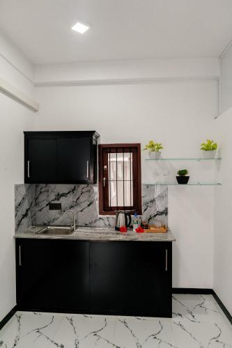 a kitchen with black cabinets and a counter top at Transit Heaven - 10 Minutes to Airport in Katunayake