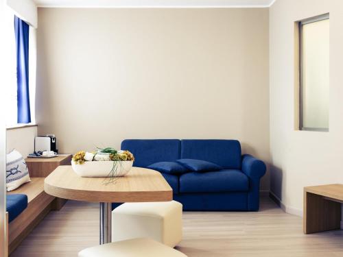 a living room with a blue couch and a table at Mercure Olbia in Olbia