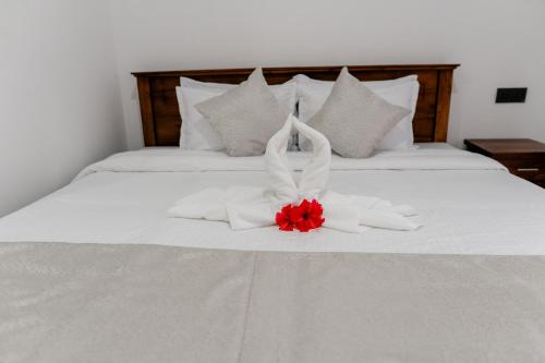 a white bed with a red flower on it at Transit Heaven - 10 Minutes to Airport in Katunayake