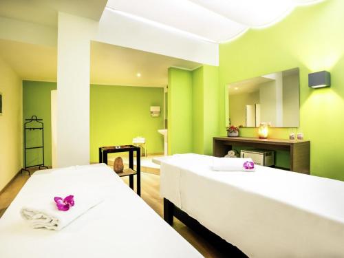 a green room with two beds and a mirror at Mercure Olbia in Olbia